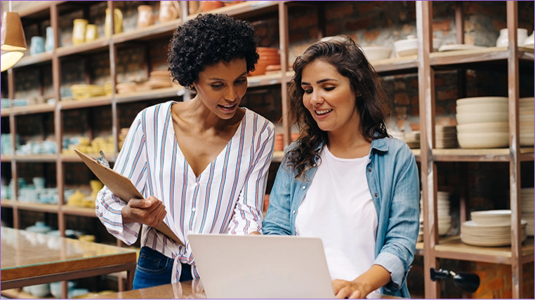 Duas mulheres verificando email corporativo no notebook
